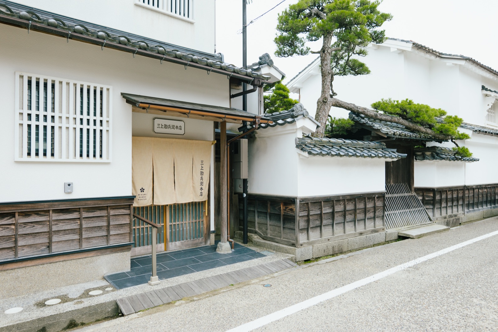 白壁の蔵と松の木が連なる、宮津・河原の町並みに佇む三上勘兵衛本店